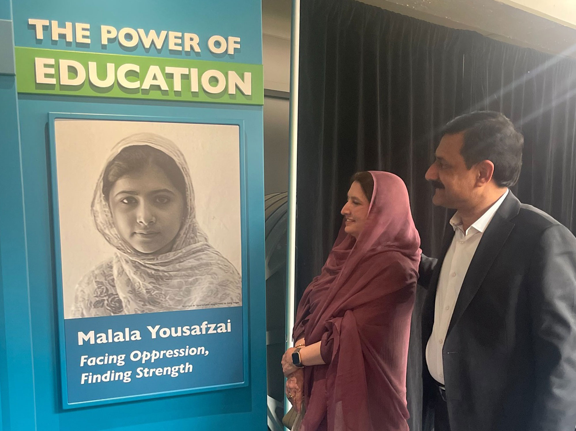 Malala's parents standing in front of her photo at the entrance to The Power of Children exhibit.